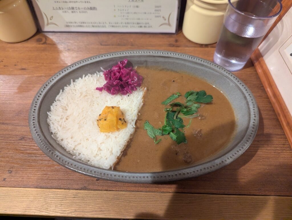 A beautiful plate of monthly special beef sinew spice curry served with long-grain rice and colorful pickles at Yosugaya in Akabanebashi, Tokyo